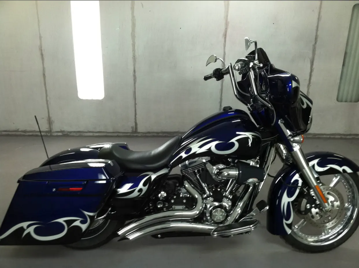 Blue touring motorcycle with custom white graphics in a paint booth